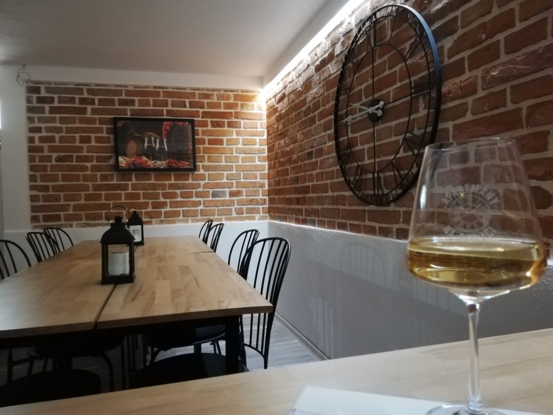 Vinný bar – posezení s cihelnou zdí a velkými hodinami